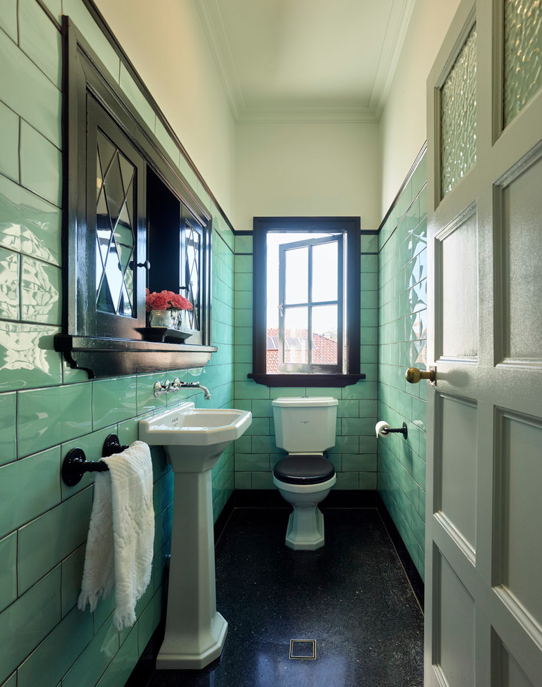 Diseño de aseo tradicional renovado con sanitario de dos piezas, baldosas y/o azulejos verdes, lavabo con pedestal y suelo negro