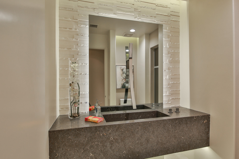 Photo of a medium sized contemporary cloakroom in Los Angeles with a one-piece toilet, white tiles, limestone tiles, beige walls, porcelain flooring, an integrated sink, limestone worktops, beige floors and grey worktops.