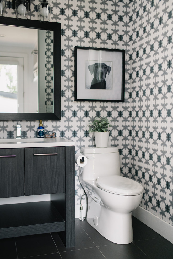 Inspiration pour un WC et toilettes traditionnel avec un placard à porte plane, des portes de placard noires, un mur multicolore, un lavabo encastré, un sol noir et un plan de toilette blanc.