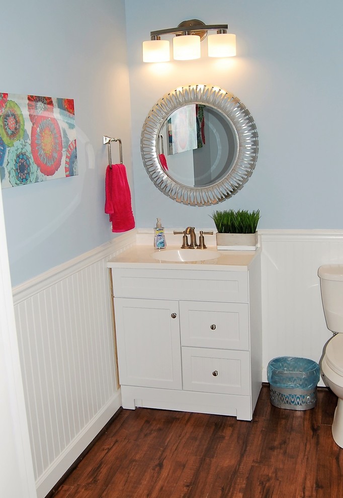 Exempel på ett mellanstort klassiskt vit vitt toalett, med skåp i shakerstil, vita skåp, en toalettstol med separat cisternkåpa, blå väggar, mörkt trägolv, ett integrerad handfat, bänkskiva i kvarts och brunt golv