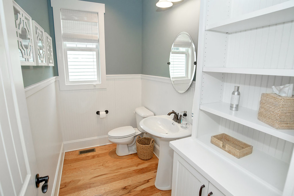 Esempio di un bagno di servizio stile americano di medie dimensioni con ante a filo, ante bianche, WC monopezzo, parquet chiaro e lavabo a colonna
