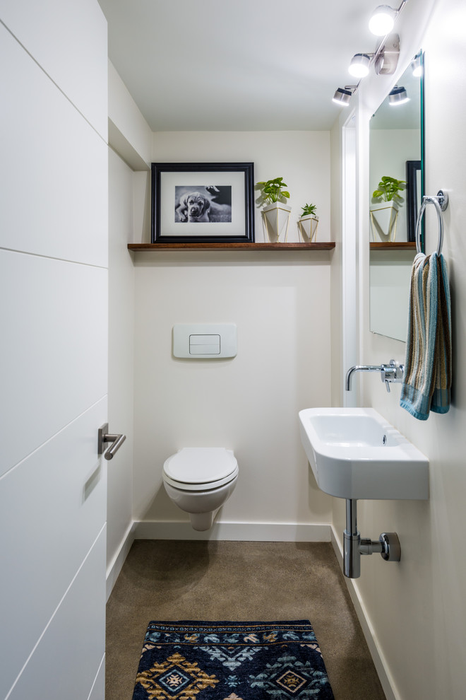 Modern inredning av ett litet toalett, med en vägghängd toalettstol, betonggolv, ett väggmonterat handfat, beige väggar och grått golv