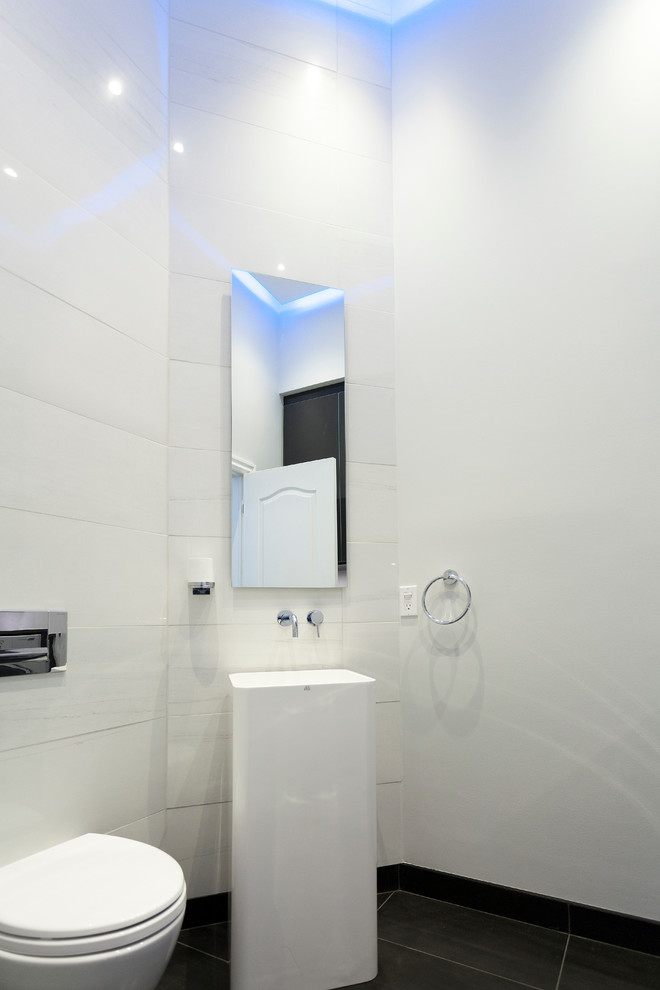 Foto på ett litet funkis toalett, med en vägghängd toalettstol, vit kakel, keramikplattor, vita väggar och klinkergolv i keramik