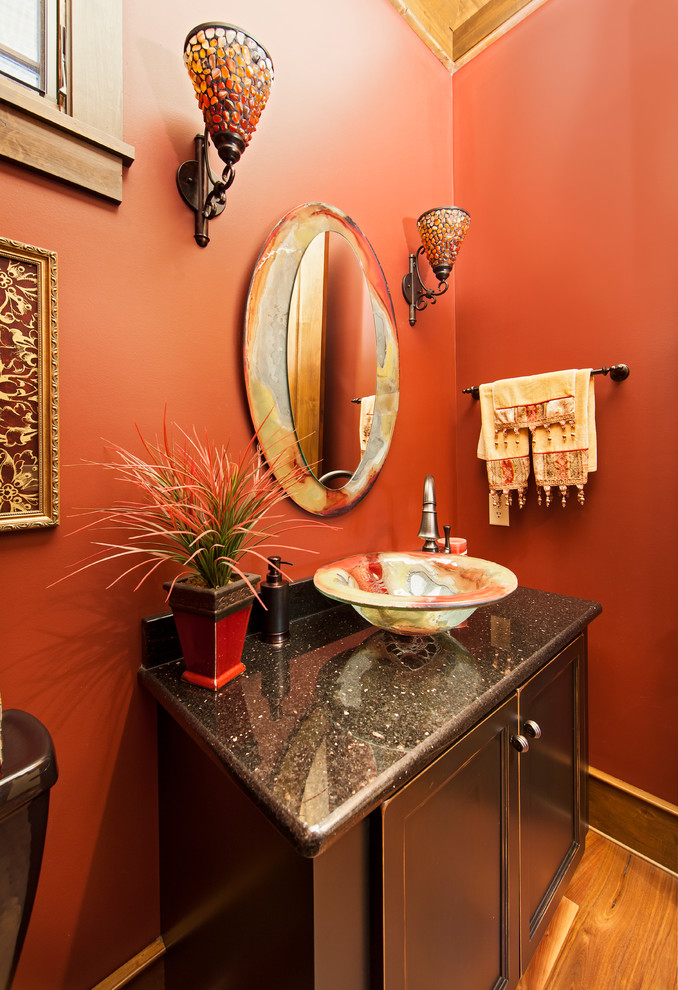 Inredning av ett modernt litet toalett, med en toalettstol med hel cisternkåpa, röda väggar, ett fristående handfat, luckor med infälld panel, bruna skåp, mellanmörkt trägolv, bänkskiva i kvarts och brunt golv