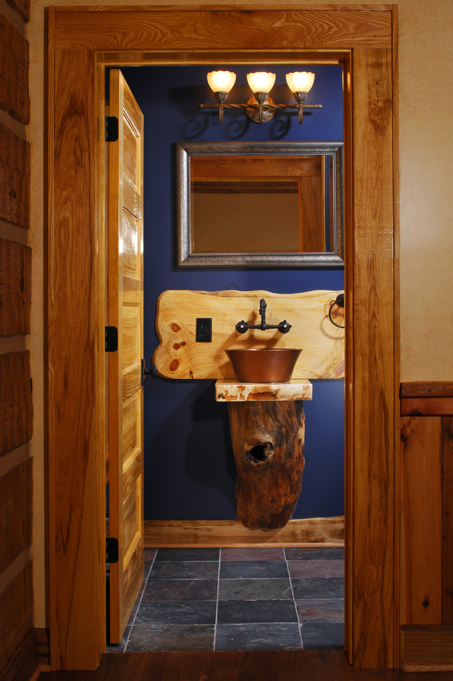 Rustik inredning av ett toalett, med ett fristående handfat och blå väggar