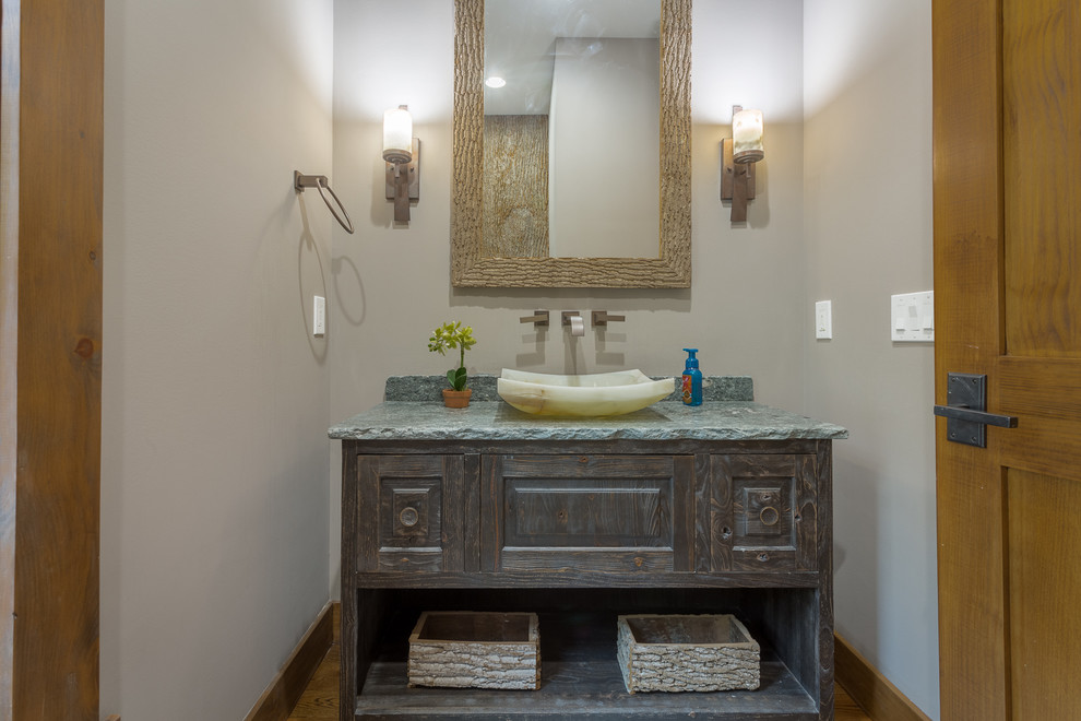 Powder room - mid-sized rustic medium tone wood floor and brown floor powder room idea in Charlotte with a vessel sink, furniture-like cabinets, a two-piece toilet, gray walls and distressed cabinets