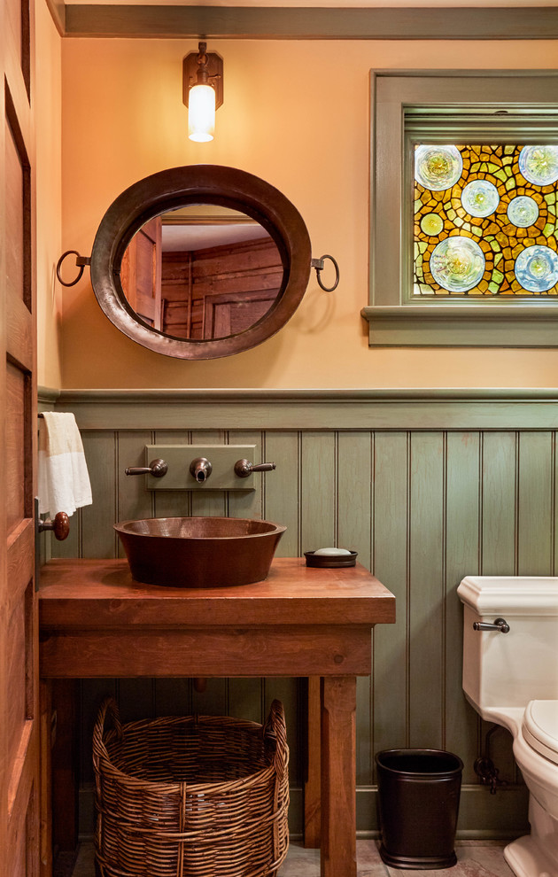 Cette photo montre un WC et toilettes montagne en bois brun avec un placard en trompe-l'oeil, un mur orange, une vasque, un plan de toilette en bois, un sol gris et un plan de toilette marron.