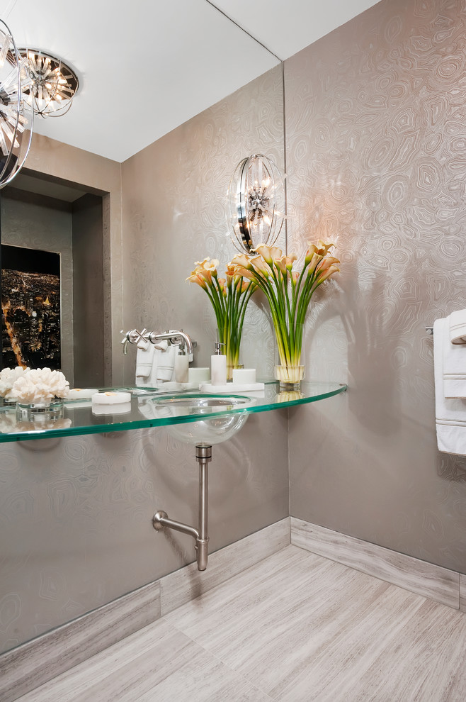 Inspiration for a medium sized classic cloakroom in Denver with glass-front cabinets, a two-piece toilet, grey tiles, stone tiles, grey walls, limestone flooring, an integrated sink and glass worktops.