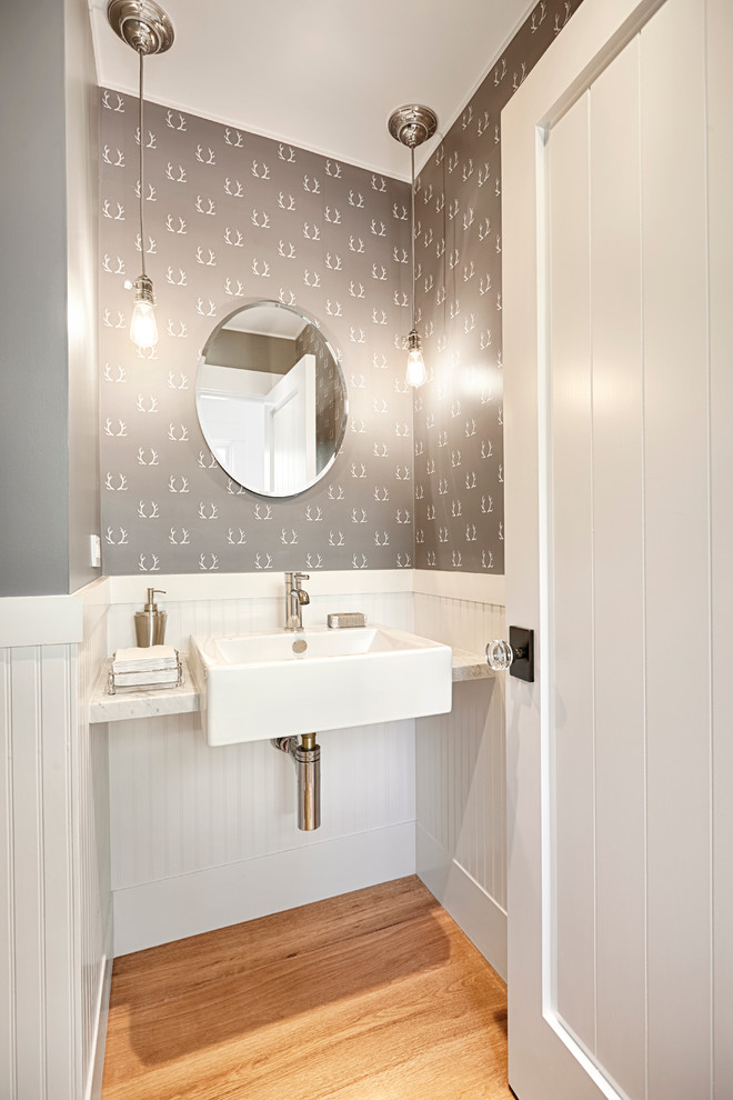Idée de décoration pour un WC et toilettes champêtre avec un plan de toilette en granite, un sol en bois brun, un mur gris et un lavabo suspendu.