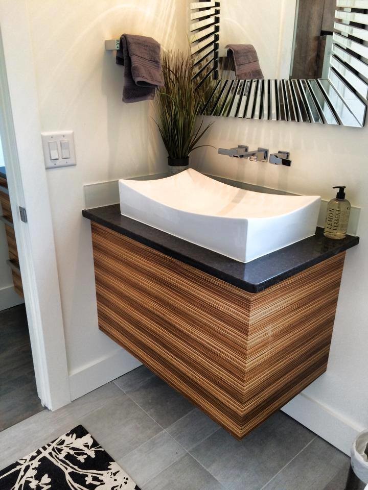 Cette photo montre un WC et toilettes tendance en bois brun de taille moyenne avec un placard à porte plane, un carrelage gris, des carreaux de céramique, un mur blanc, un sol en carrelage de céramique, une vasque et un plan de toilette noir.