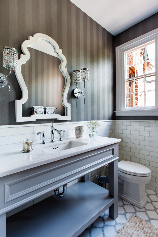 Klassisk inredning av ett stort vit vitt toalett, med öppna hyllor, grå skåp, en toalettstol med hel cisternkåpa, vit kakel, tunnelbanekakel, grå väggar, marmorgolv, ett undermonterad handfat, marmorbänkskiva och flerfärgat golv