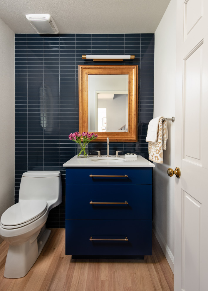 Пример оригинального дизайна: маленький туалет в современном стиле с плоскими фасадами, синими фасадами, унитазом-моноблоком, синей плиткой, керамической плиткой, белыми стенами, светлым паркетным полом, врезной раковиной, столешницей из искусственного кварца, белой столешницей и бежевым полом для на участке и в саду