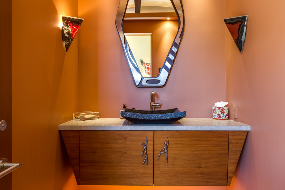 На фото: туалет среднего размера в восточном стиле с фасадами цвета дерева среднего тона, оранжевыми стенами, настольной раковиной, столешницей из гранита и серой столешницей с