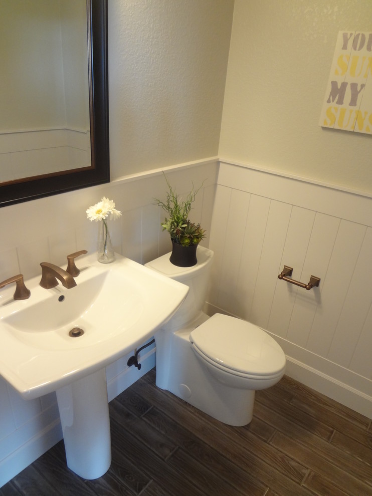Réalisation d'un WC et toilettes tradition de taille moyenne avec WC à poser, un mur blanc, un sol en bois brun et un lavabo de ferme.