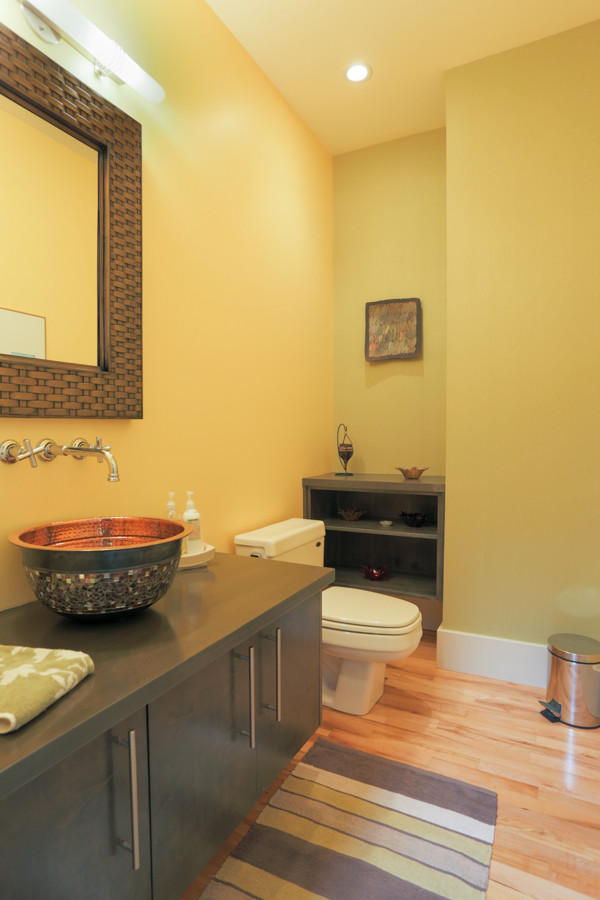 Ejemplo de aseo contemporáneo con lavabo sobreencimera y paredes amarillas