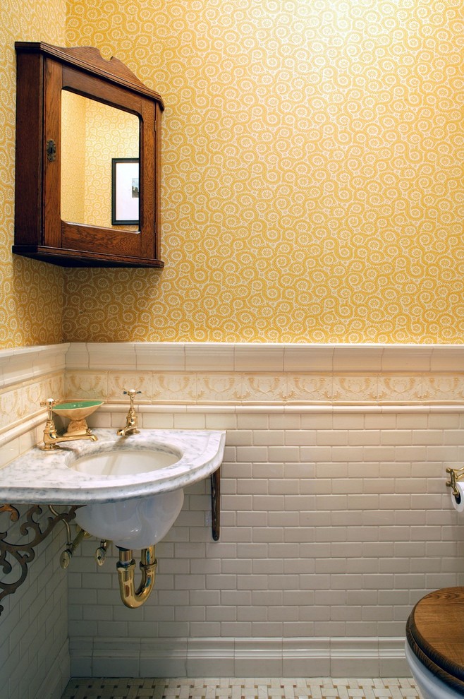 This is an example of a small rural cloakroom in New York with a two-piece toilet, white tiles, ceramic tiles, yellow walls, a submerged sink, marble worktops and marble flooring.