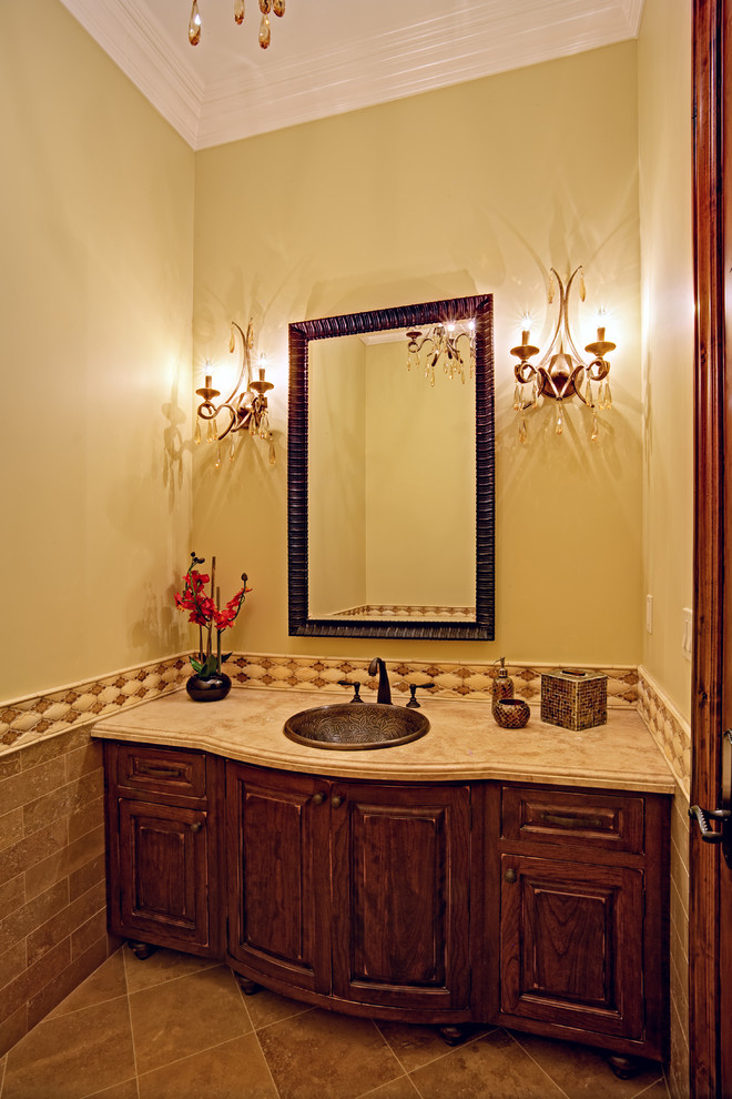 Foto på ett mellanstort vintage toalett, med ett nedsänkt handfat, skåp i mörkt trä, marmorbänkskiva, brun kakel, stenkakel, beige väggar, travertin golv och möbel-liknande