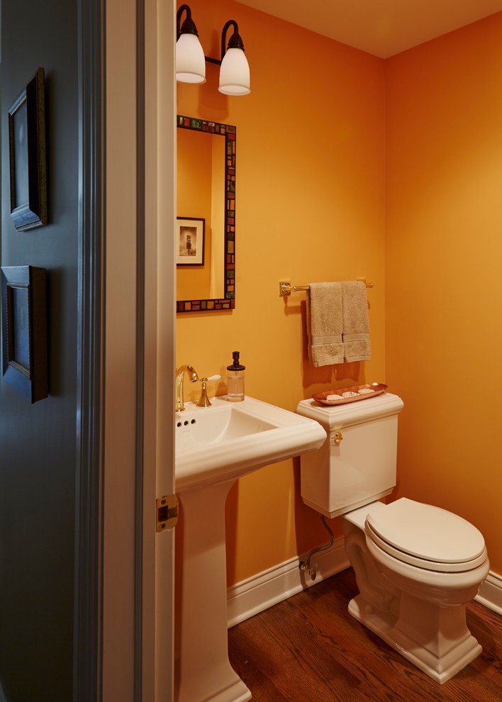 Kleine Eklektische Gästetoilette mit Wandtoilette mit Spülkasten, braunem Holzboden, Sockelwaschbecken und gelber Wandfarbe in Chicago