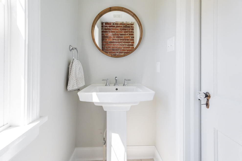 Inredning av ett klassiskt litet toalett, med vita väggar, ett piedestal handfat och beiget golv