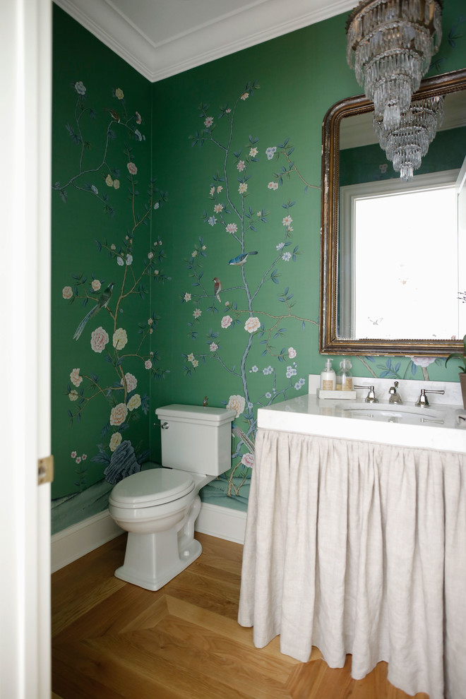 Immagine di un bagno di servizio classico con WC a due pezzi, pareti verdi, parquet chiaro e lavabo sottopiano