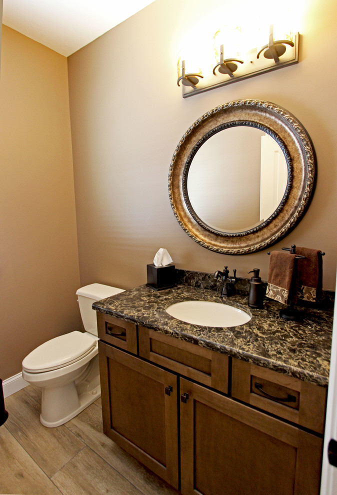 Cette image montre un petit WC et toilettes traditionnel avec un placard à porte plane, des portes de placard marrons, un carrelage beige et un plan de toilette en quartz modifié.