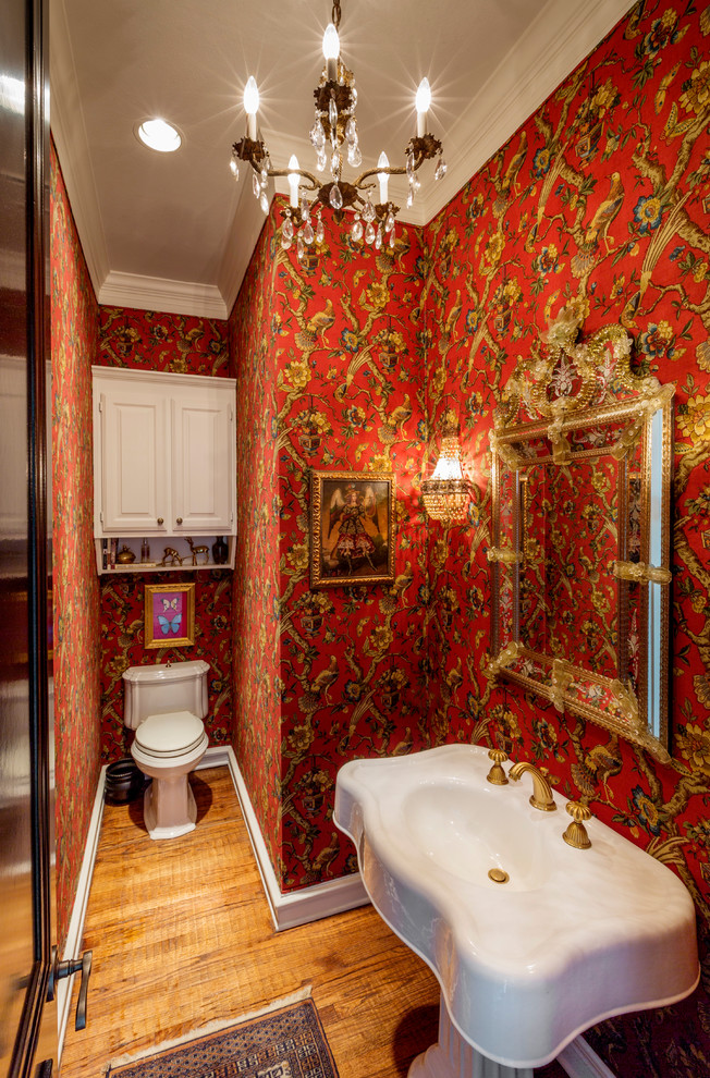 Klassische Gästetoilette mit roter Wandfarbe, braunem Holzboden, Sockelwaschbecken und braunem Boden in Dallas