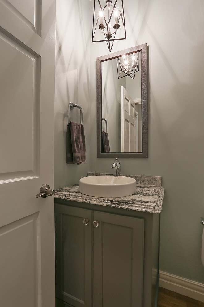 Cette photo montre un WC et toilettes chic avec un placard à porte plane, WC séparés, un carrelage vert, parquet clair, une vasque et un plan de toilette en quartz modifié.