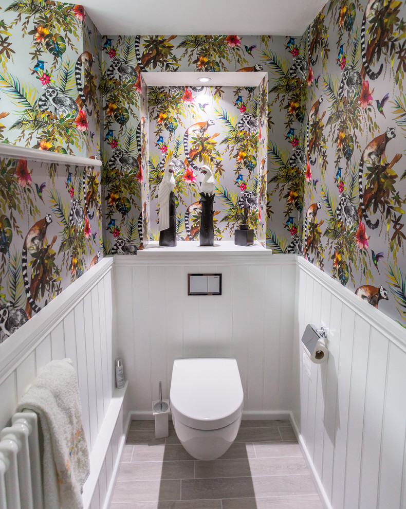 Cette image montre un WC suspendu traditionnel avec un mur multicolore et un sol gris.