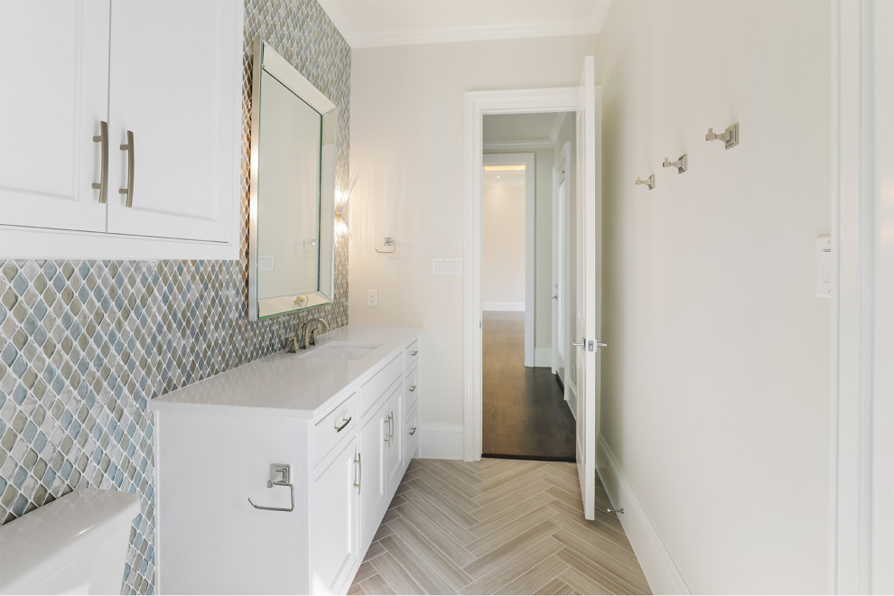 Пример оригинального дизайна: туалет среднего размера в стиле неоклассика (современная классика) с фасадами с утопленной филенкой, белыми фасадами, унитазом-моноблоком, разноцветной плиткой, плиткой мозаикой, бежевыми стенами, полом из керамической плитки, врезной раковиной, столешницей из искусственного кварца, бежевым полом, белой столешницей и встроенной тумбой
