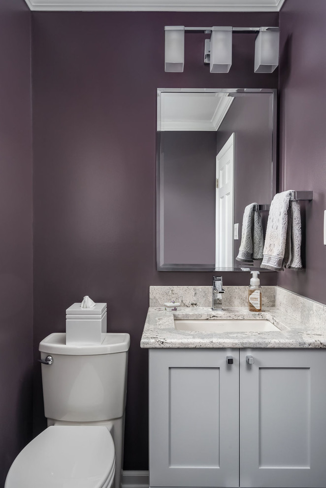 Aménagement d'un petit WC et toilettes classique avec un placard à porte shaker, des portes de placard grises, WC à poser, un mur violet, parquet foncé, un lavabo encastré, un plan de toilette en quartz modifié, un sol marron et un plan de toilette gris.