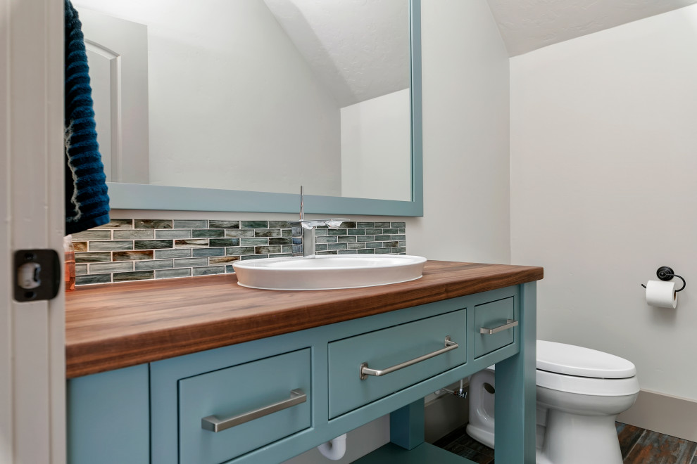 Idéer för att renovera ett mellanstort lantligt brun brunt toalett, med släta luckor, turkosa skåp, blå kakel, mosaik, grå väggar, målat trägolv, ett nedsänkt handfat, träbänkskiva och flerfärgat golv