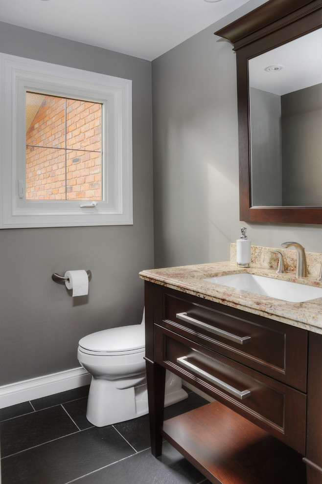 Klassisk inredning av ett mellanstort toalett, med ett undermonterad handfat, luckor med infälld panel, granitbänkskiva, grå väggar, skiffergolv och skåp i mörkt trä