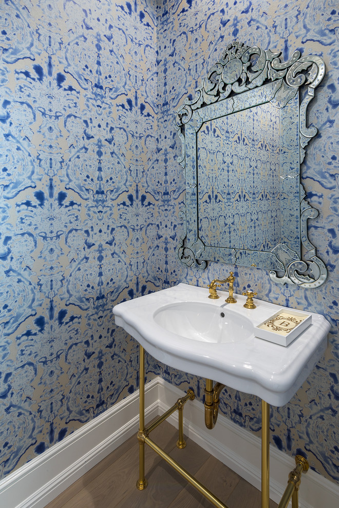 Esempio di un piccolo bagno di servizio classico con WC monopezzo, pareti blu, pavimento in legno massello medio, lavabo a consolle e top bianco