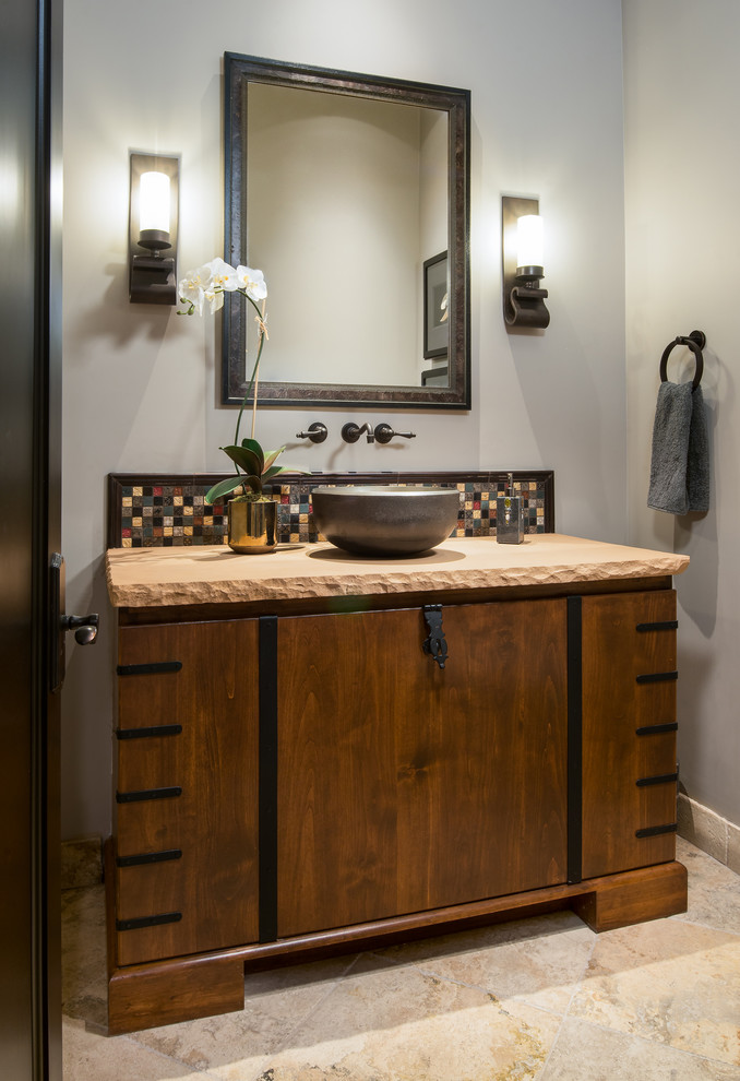 Inspiration for a mid-sized transitional multicolored tile and mosaic tile travertine floor and beige floor powder room remodel in Phoenix with flat-panel cabinets, dark wood cabinets, gray walls, a vessel sink and beige countertops