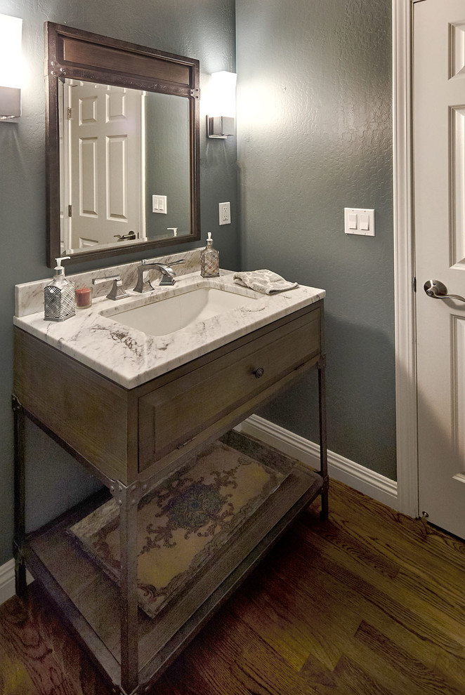 Cette image montre un petit WC et toilettes traditionnel avec un placard en trompe-l'oeil, des portes de placard grises, WC séparés, un mur bleu, parquet foncé, un lavabo encastré, un plan de toilette en marbre et un sol marron.