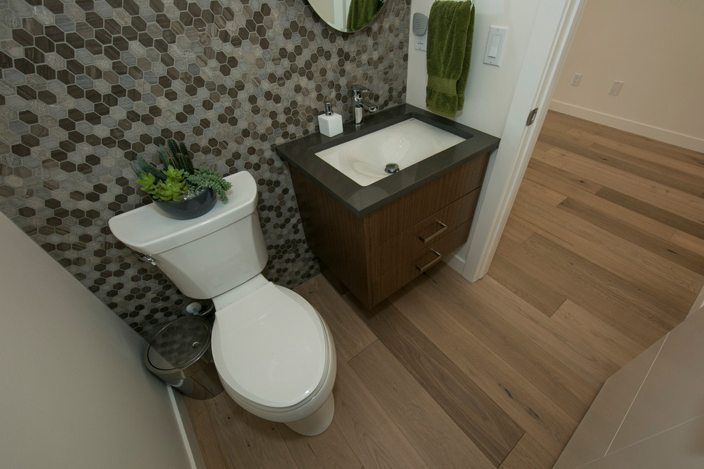 Photo of a large contemporary cloakroom in Edmonton with a submerged sink, flat-panel cabinets, medium wood cabinets, engineered stone worktops, a one-piece toilet, multi-coloured tiles, beige walls, mosaic tiles and light hardwood flooring.