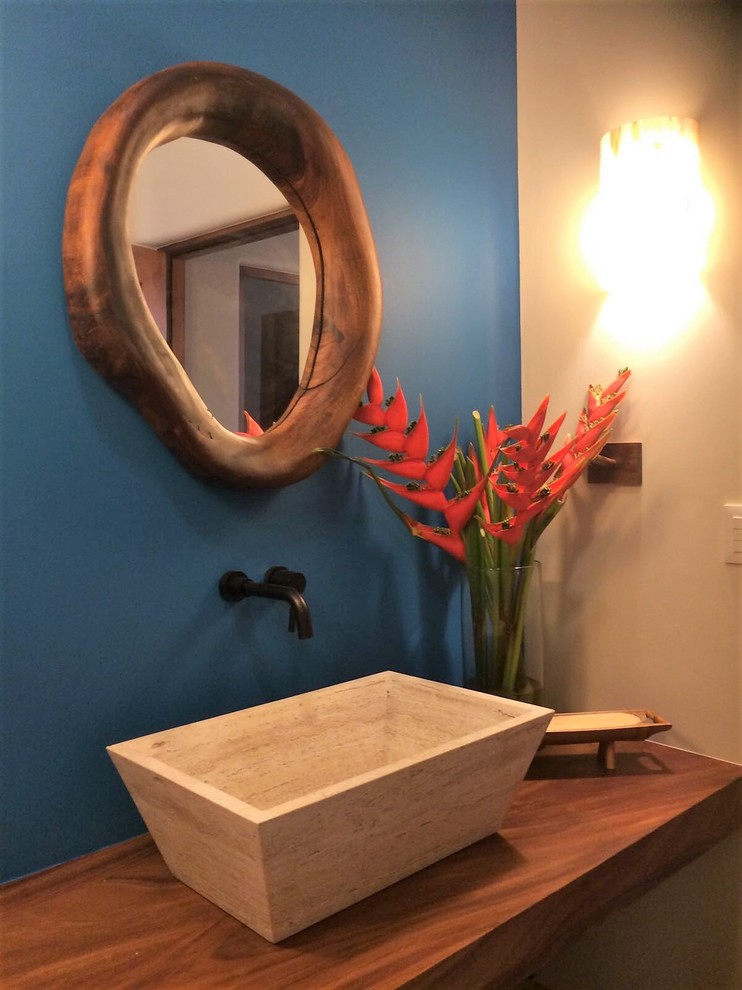 На фото: большой туалет в морском стиле с синими стенами, настольной раковиной, столешницей из дерева и коричневой столешницей