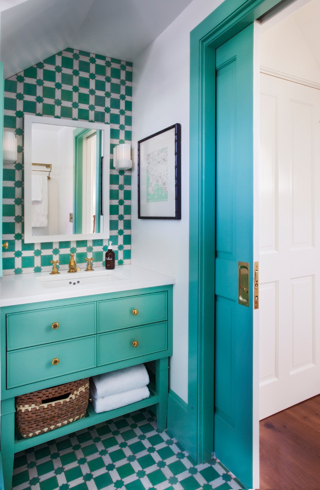 Cette image montre un WC et toilettes ethnique avec des portes de placards vertess, un carrelage bleu, un carrelage vert, un mur blanc, un lavabo encastré, un sol vert, un placard à porte affleurante et un plan de toilette blanc.