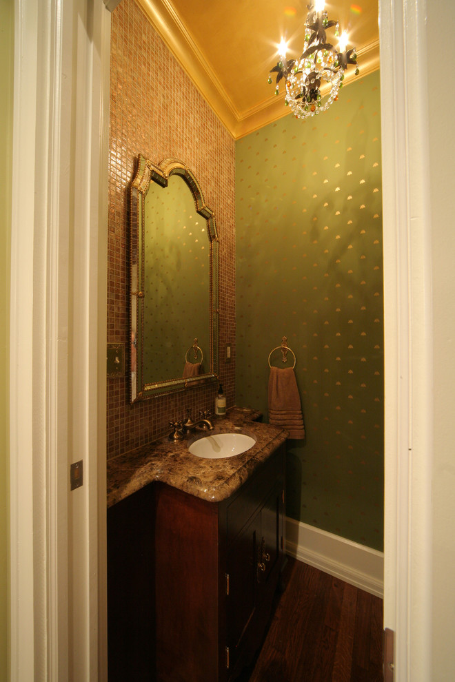 Kleine Klassische Gästetoilette mit Schrankfronten mit vertiefter Füllung, braunen Fliesen, grüner Wandfarbe, braunem Holzboden, integriertem Waschbecken und brauner Waschtischplatte in Sonstige