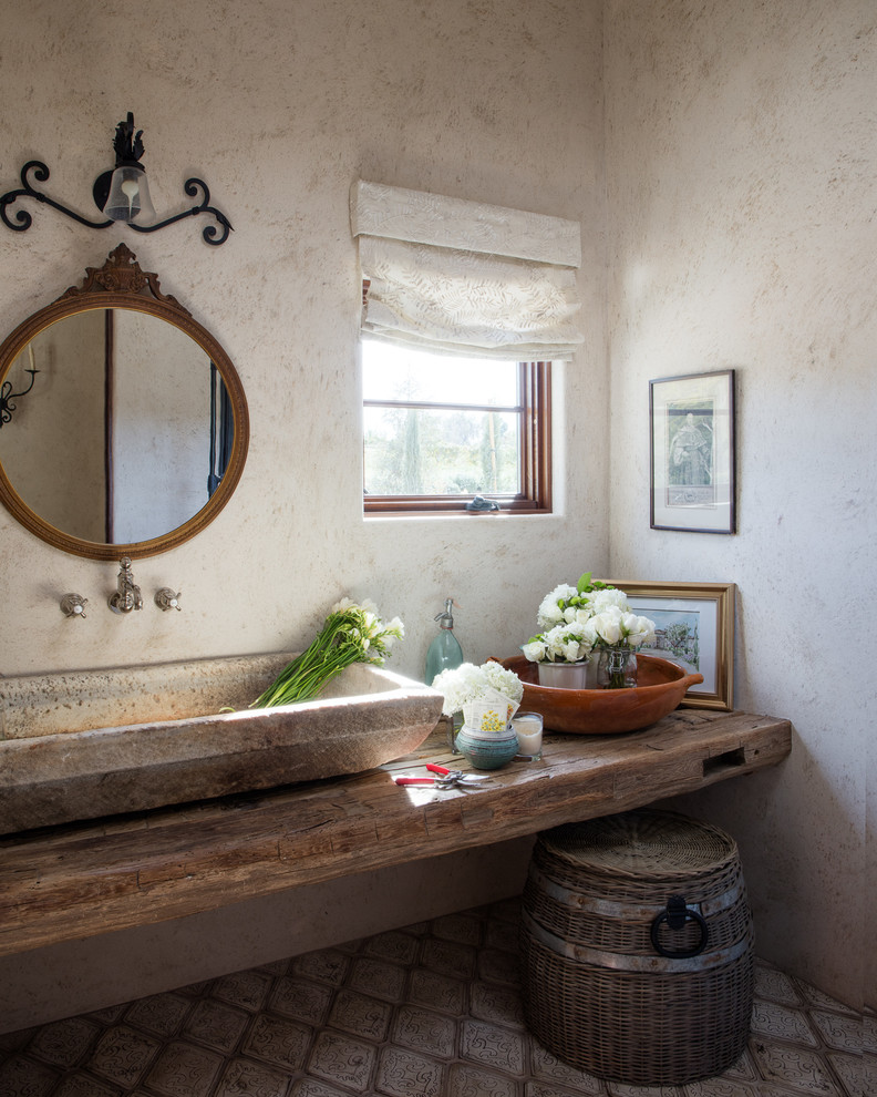 Стильный дизайн: туалет в средиземноморском стиле с бежевыми стенами, настольной раковиной, столешницей из дерева и коричневой столешницей - последний тренд
