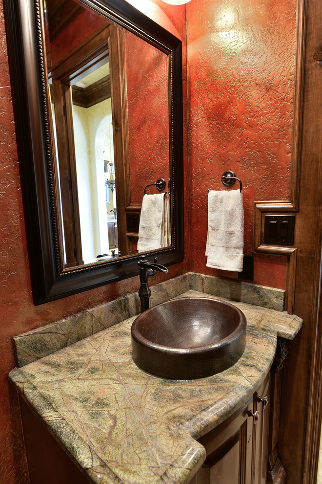 Mittelgroße Mediterrane Gästetoilette mit verzierten Schränken, braunen Schränken, Toilette mit Aufsatzspülkasten, roter Wandfarbe, Travertin, Einbauwaschbecken, Granit-Waschbecken/Waschtisch und beigem Boden in Houston