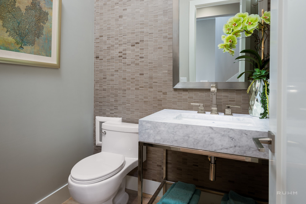This is an example of a contemporary cloakroom in Orange County with a pedestal sink, marble worktops, a one-piece toilet, grey tiles, mosaic tiles, grey walls and open cabinets.