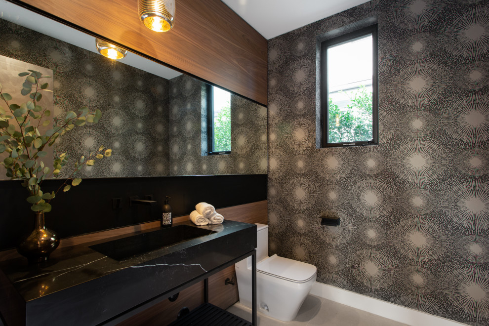 Modern inredning av ett stort svart svart toalett, med svarta skåp, en toalettstol med hel cisternkåpa, flerfärgade väggar, betonggolv, ett integrerad handfat, marmorbänkskiva och grått golv