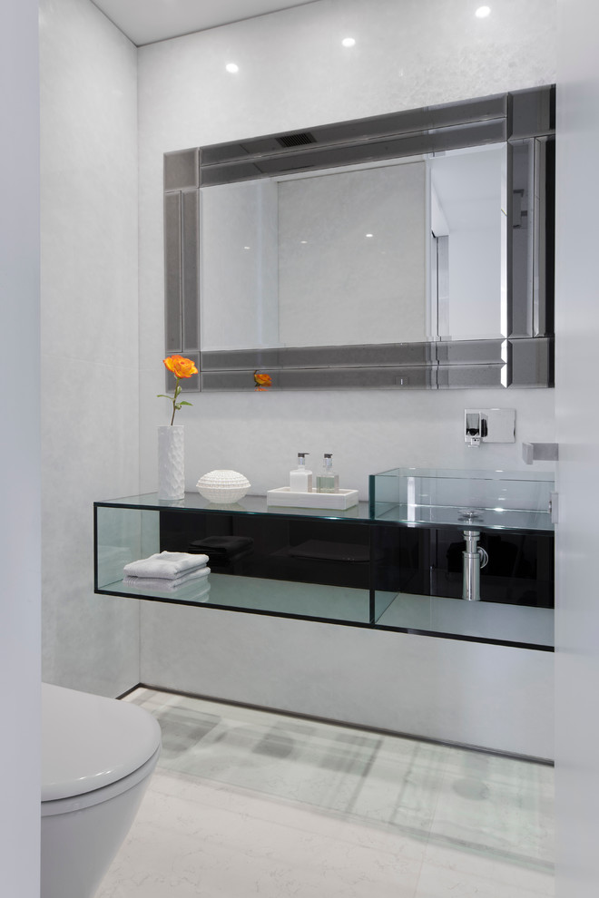 Foto di un piccolo bagno di servizio moderno con WC monopezzo, pareti grigie, lavabo integrato e top in vetro