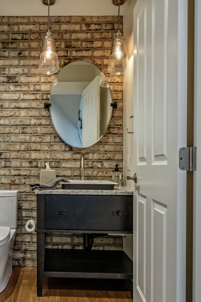 Inspiration for a medium sized urban cloakroom in Vancouver with flat-panel cabinets, black cabinets, a two-piece toilet, medium hardwood flooring, a built-in sink, granite worktops, brown floors and grey worktops.