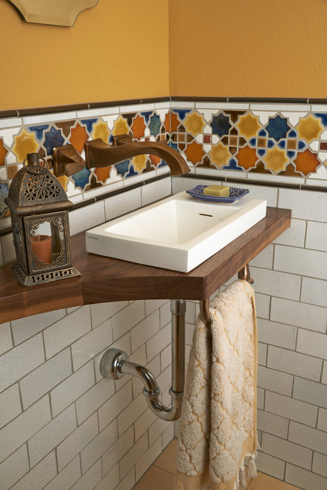 Идея дизайна: туалет в средиземноморском стиле с накладной раковиной, столешницей из дерева и коричневой столешницей
