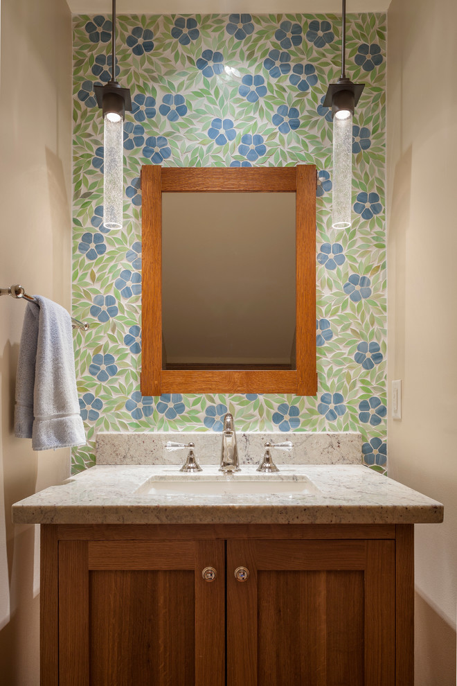 Idée de décoration pour un WC et toilettes craftsman en bois brun de taille moyenne avec un placard à porte shaker, un carrelage bleu, un carrelage vert, mosaïque, un mur beige, un lavabo encastré et un plan de toilette en calcaire.