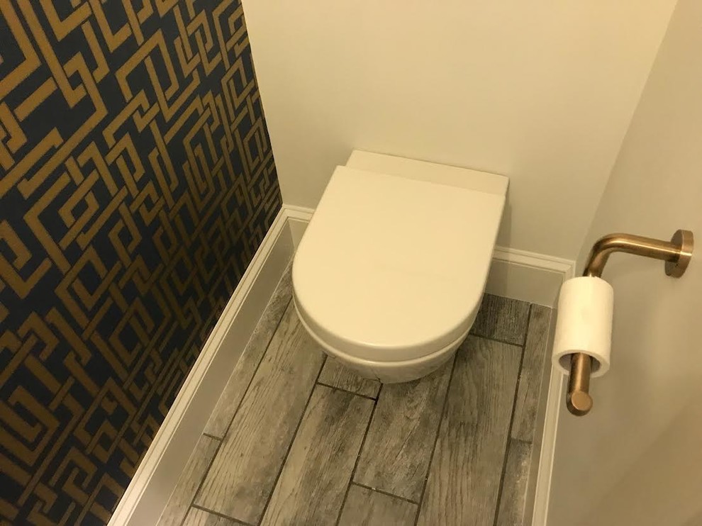 Modern inredning av ett litet toalett, med en toalettstol med hel cisternkåpa, vit kakel, porslinskakel, flerfärgade väggar, klinkergolv i porslin, ett väggmonterat handfat, bänkskiva i akrylsten och grått golv
