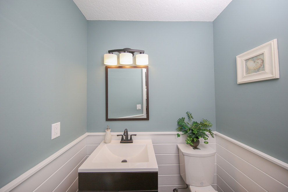 タンパにある低価格の小さなトランジショナルスタイルのおしゃれなトイレ・洗面所 (濃色木目調キャビネット、白いタイル、青い壁、一体型シンク、分離型トイレ) の写真