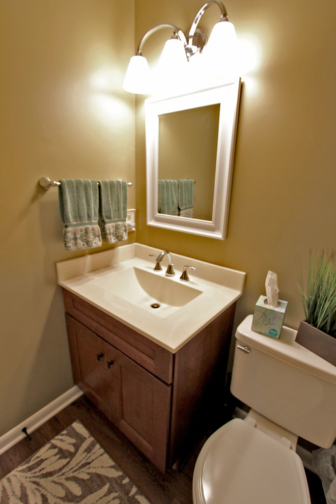 Idee per un piccolo bagno di servizio classico con ante con riquadro incassato, ante in legno scuro, pareti gialle, lavabo integrato, top in marmo e top beige